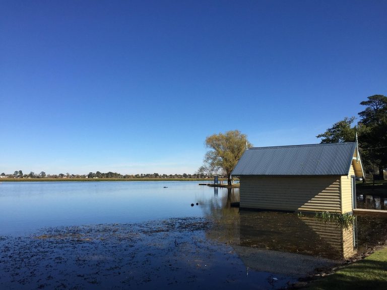 Boathouse on Lake Wendouree in Ballarat, reflected on calm water under a clear blue sky.