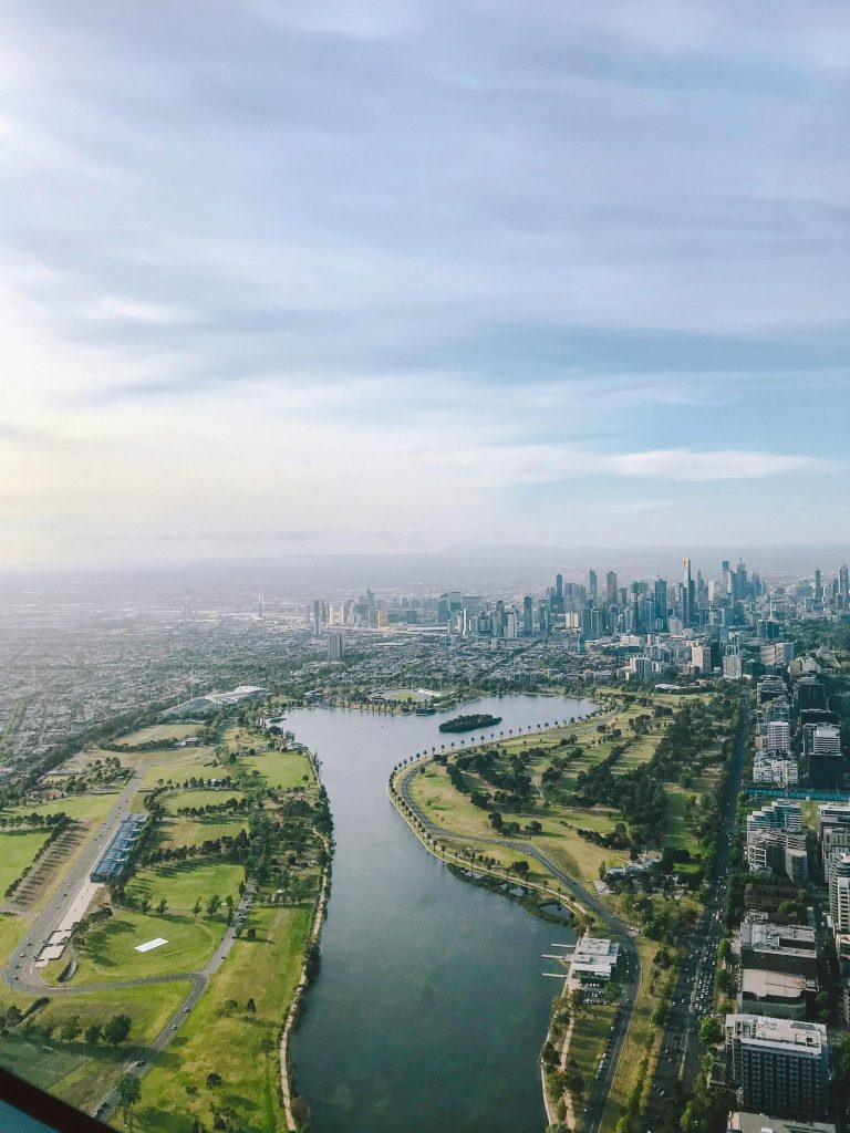 Aerial view of the Yarra River winding through Melbourne’s parklands toward the CBD skyline.