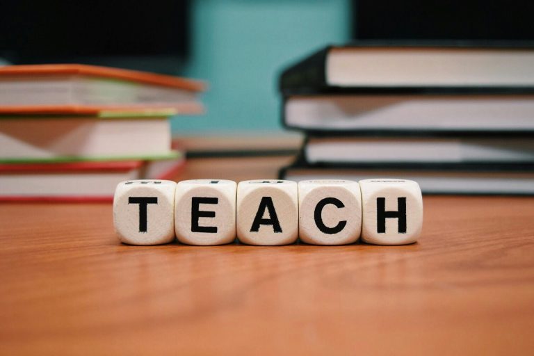 Books and letter tiles spelling TEACH on a desk for a Newcastle NSW school guide