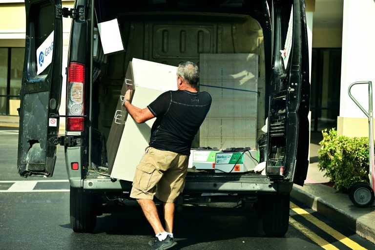 Man unloading furniture from a moving van outside a home in North Geelong