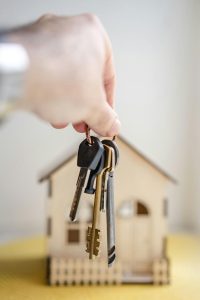 Home loan broker Ballarat — hand holding house keys in front of a small house model