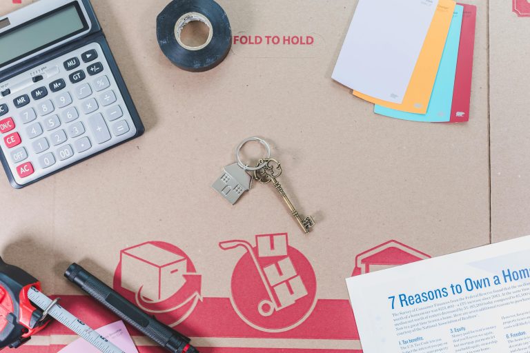 Flat lay of home loan and refinance planning essentials including keys, calculator, and contract papers.