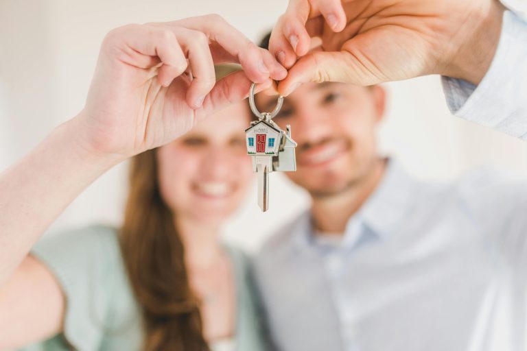 Smiling young couple holding keys after purchasing their first investment property, used for a Ballarat rentvesting case study.